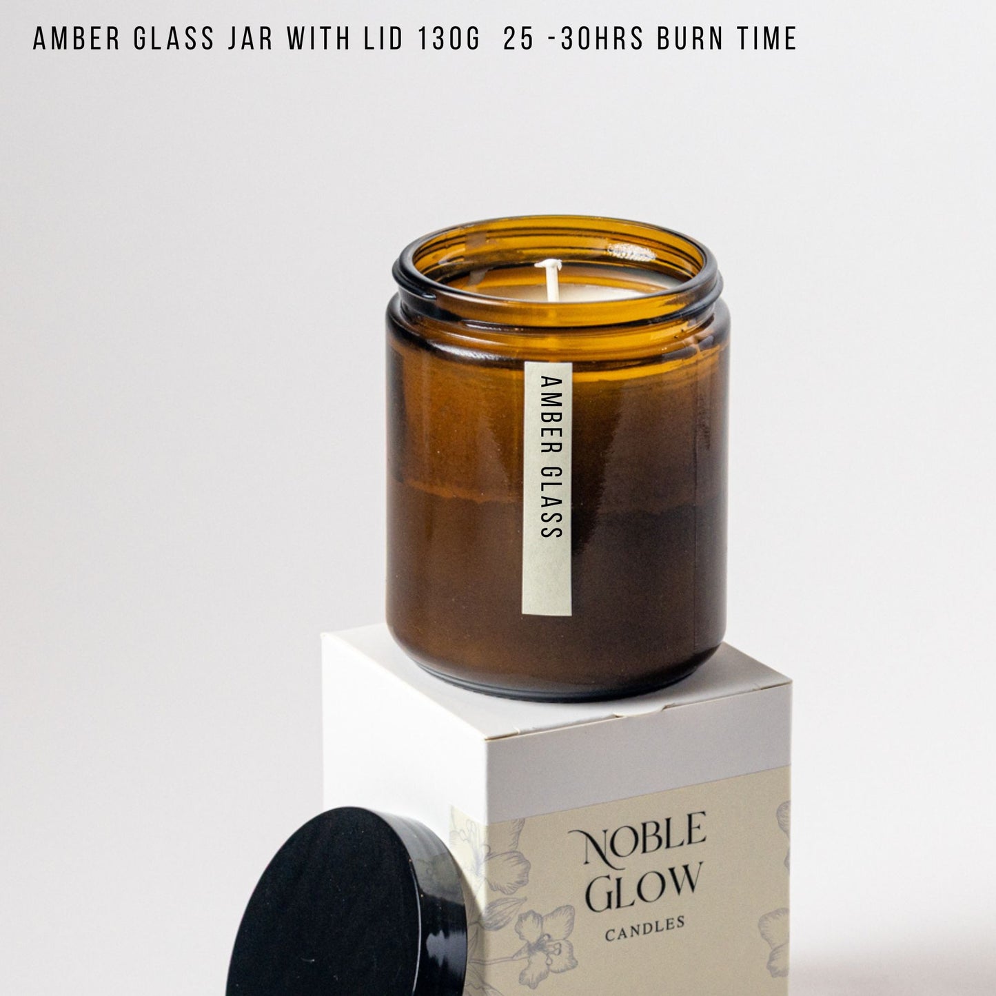 Amber glass jar candle with lid on a white background, featuring 'Noble Glow Candles' branding.
