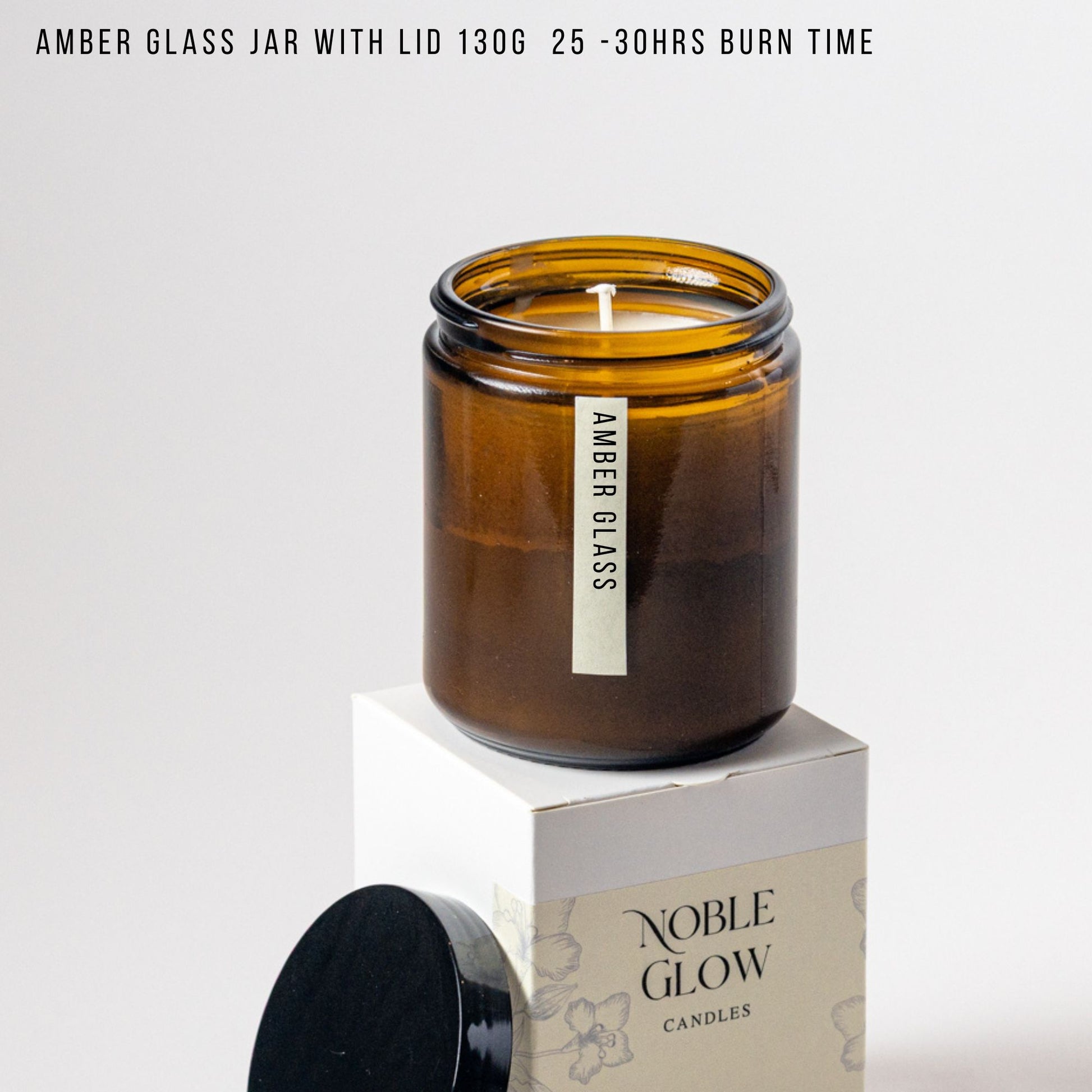 Amber glass jar candle with lid on a white background, featuring 'Noble Glow Candles' branding.