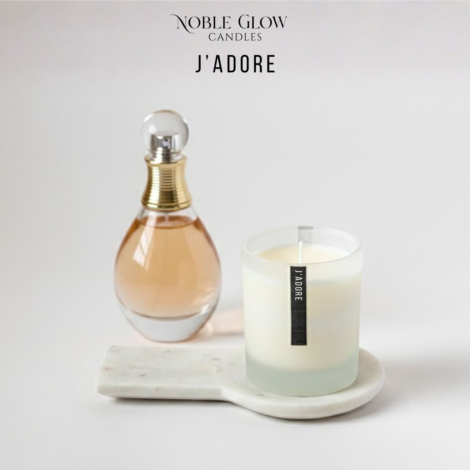 Perfume bottle and candle on a marble tray with 'Noble Glow Candles J'Adore' branding.