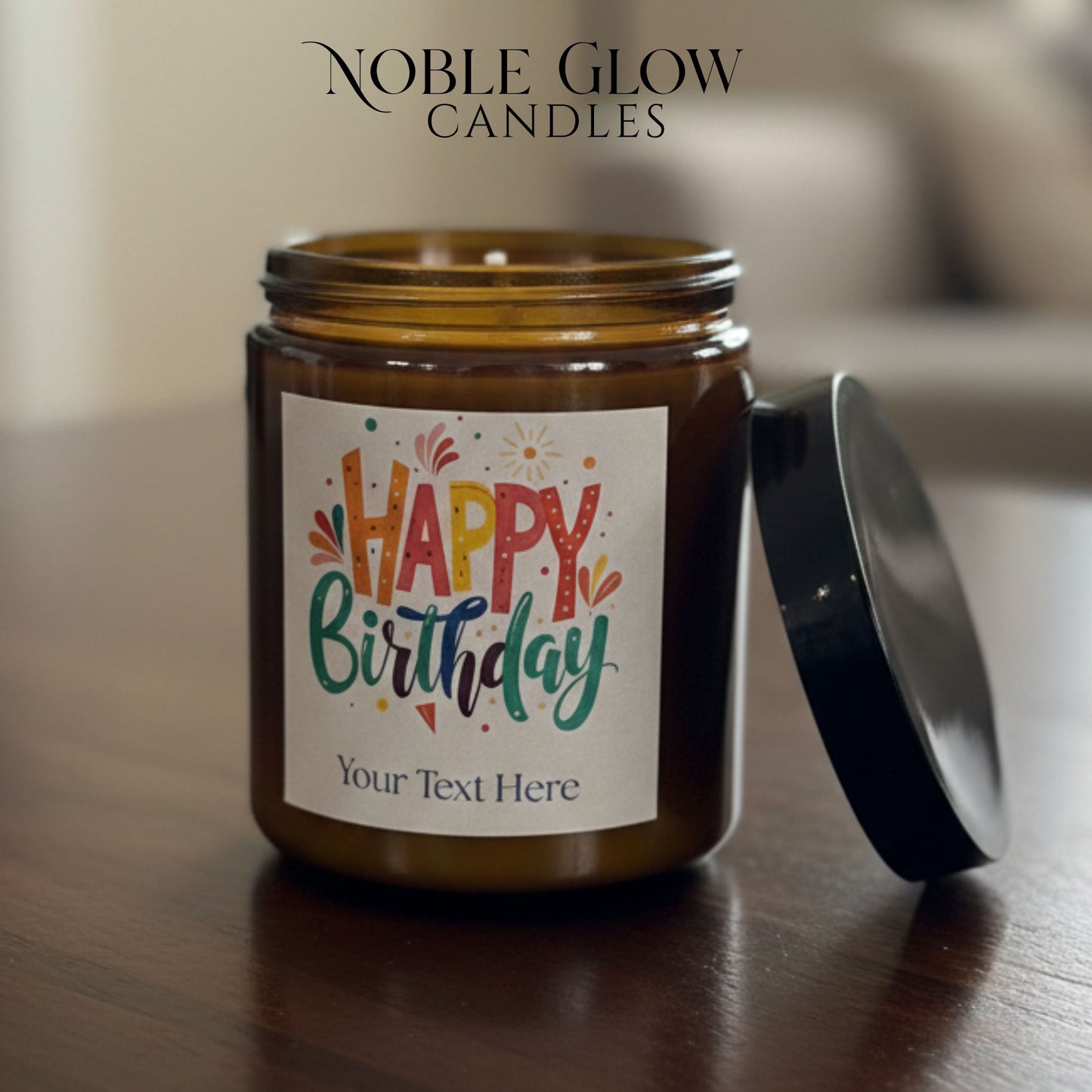 Candle jar with 'Happy Birthday' label on a wooden surface, featuring Noble Glow Candles branding.