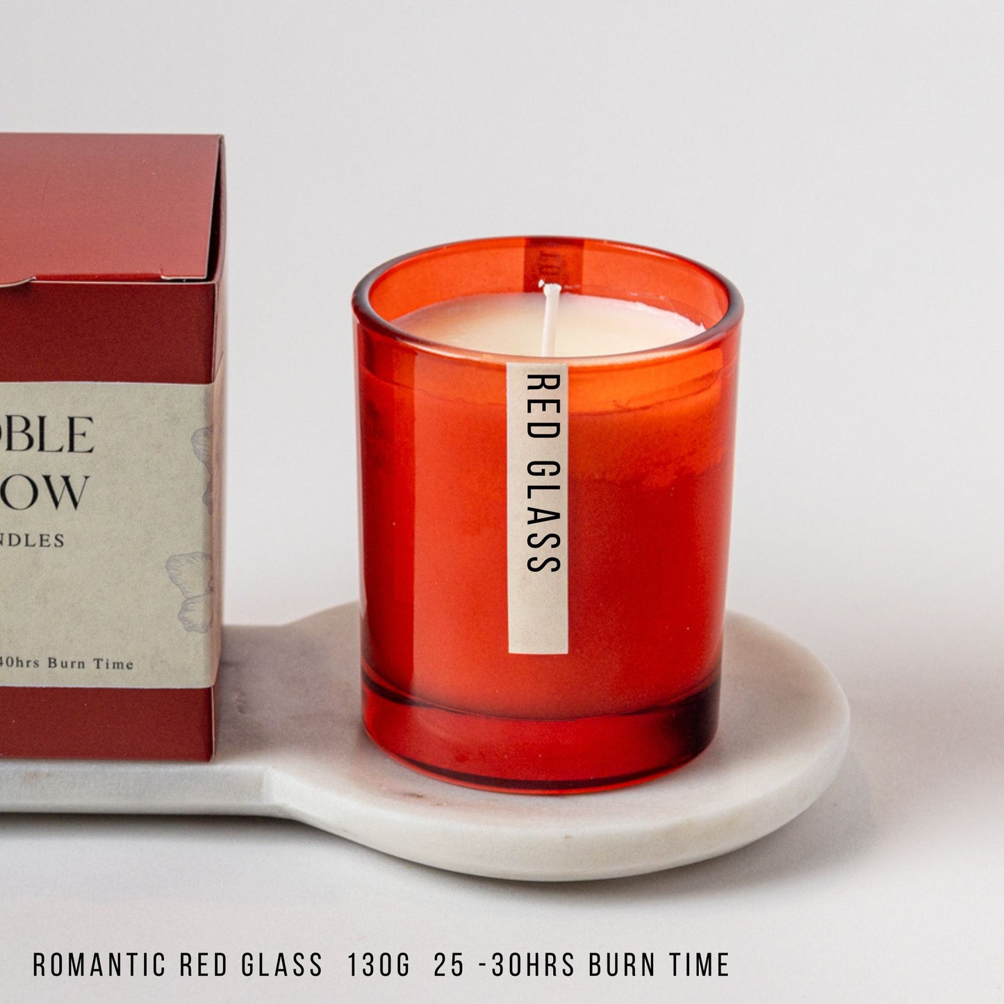 Red glass candle with 'Red Glass' label next to a box on a white surface