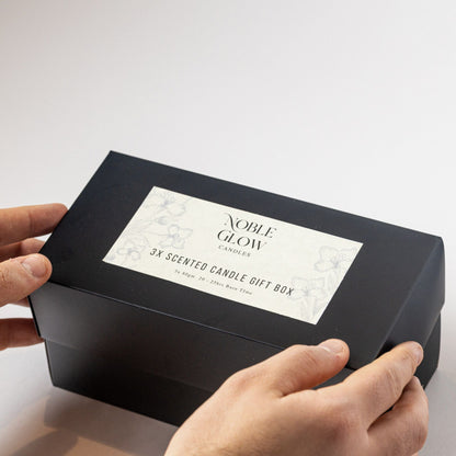 Black gift box with 'Noble Glow' label held by a hand on a white background