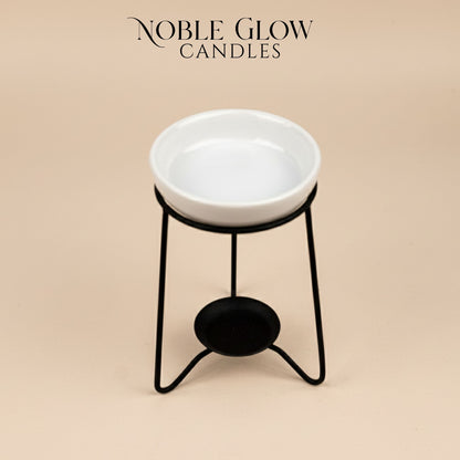 White ceramic bowl on a black metal stand with 'Noble Glow Candles' branding on a beige background.