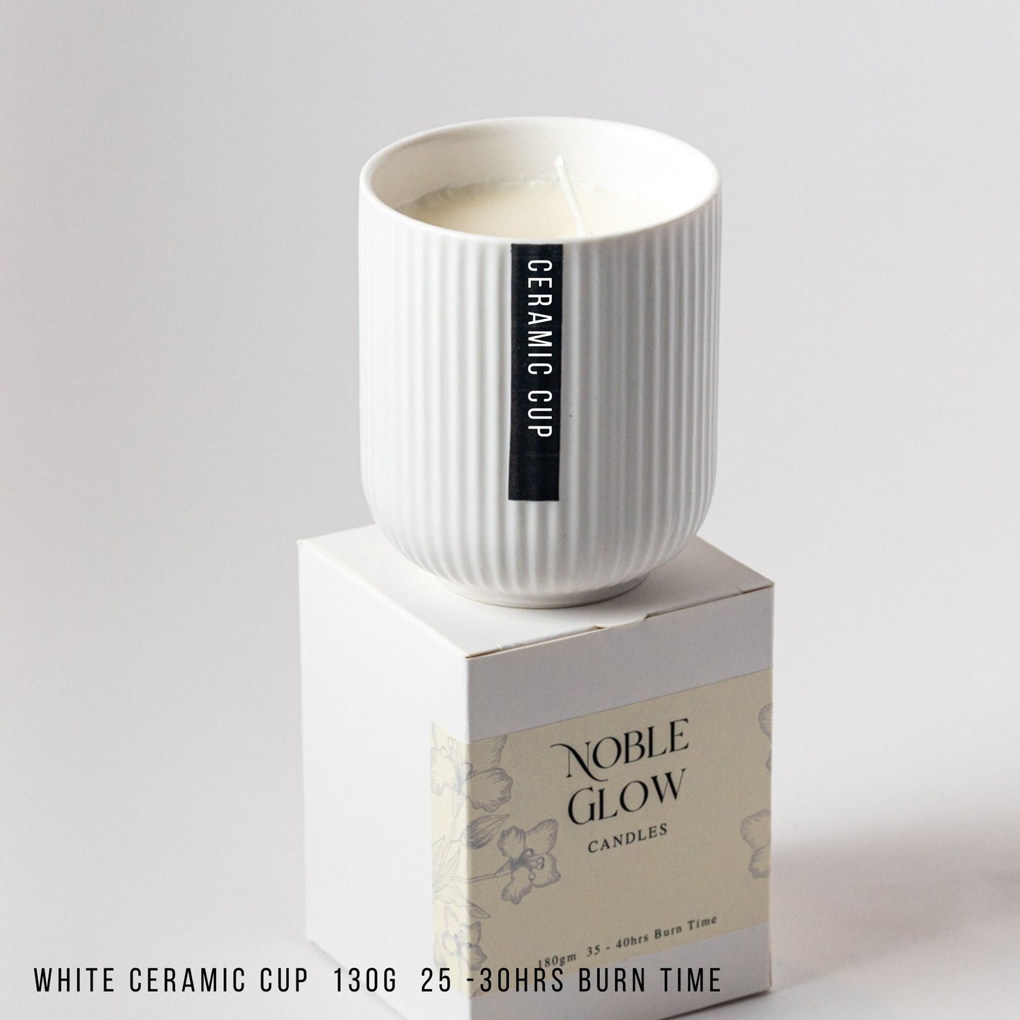 White ceramic cup on a box with 'Noble Glow Candles' branding on a gray background