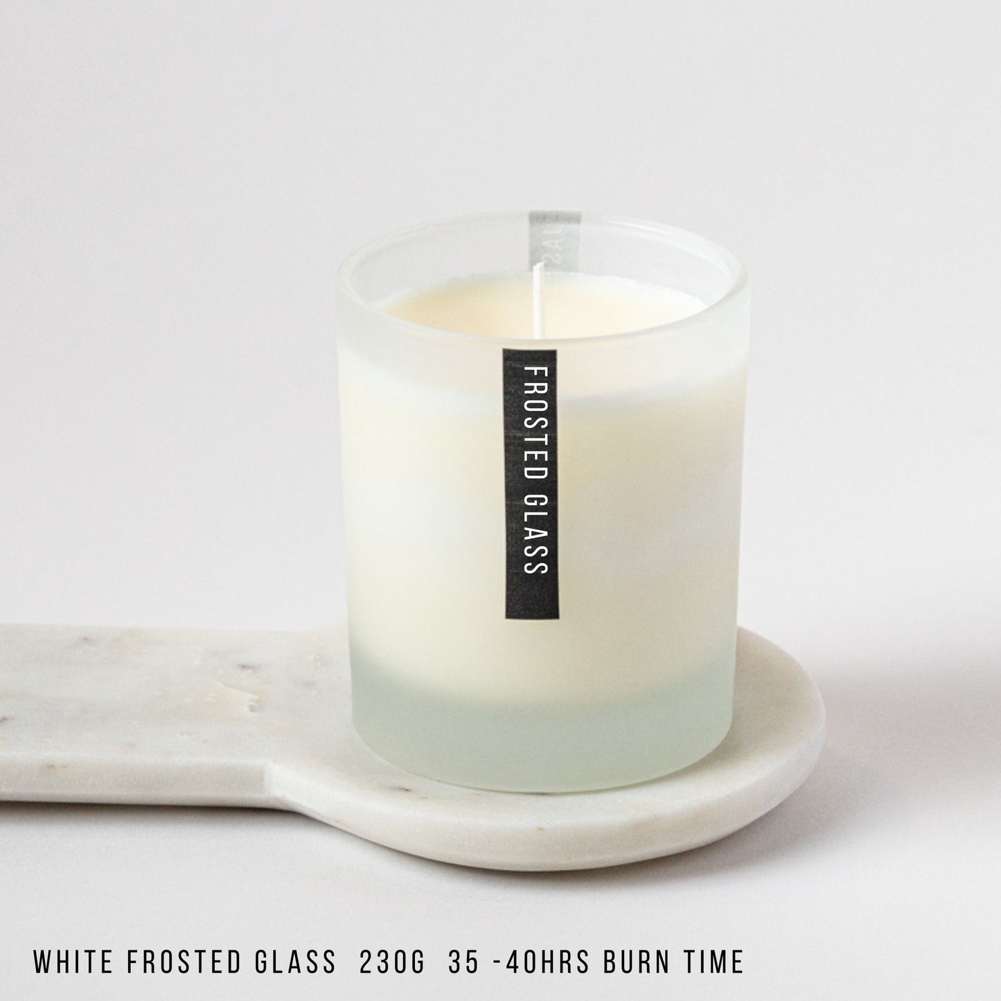 White frosted glass candle on a marble tray with a label on a white background